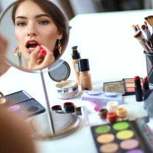 A woman is putting lipstick on her lips