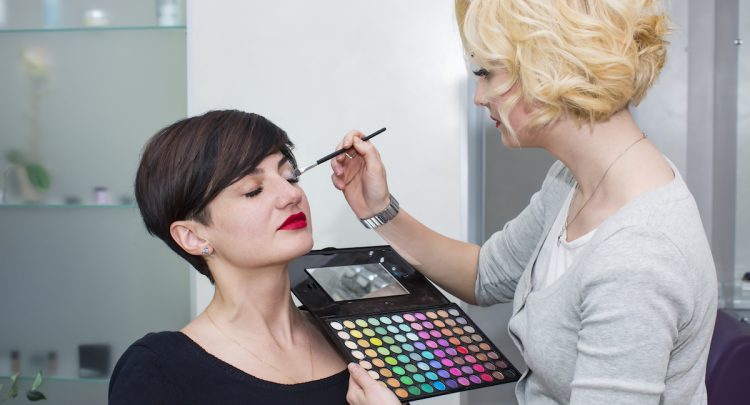 A woman is getting her face painted by an artist.