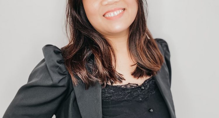 A woman in black shirt and jacket smiling.